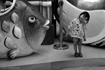 Little smiling Chinese girl near the statue of a giant fish.