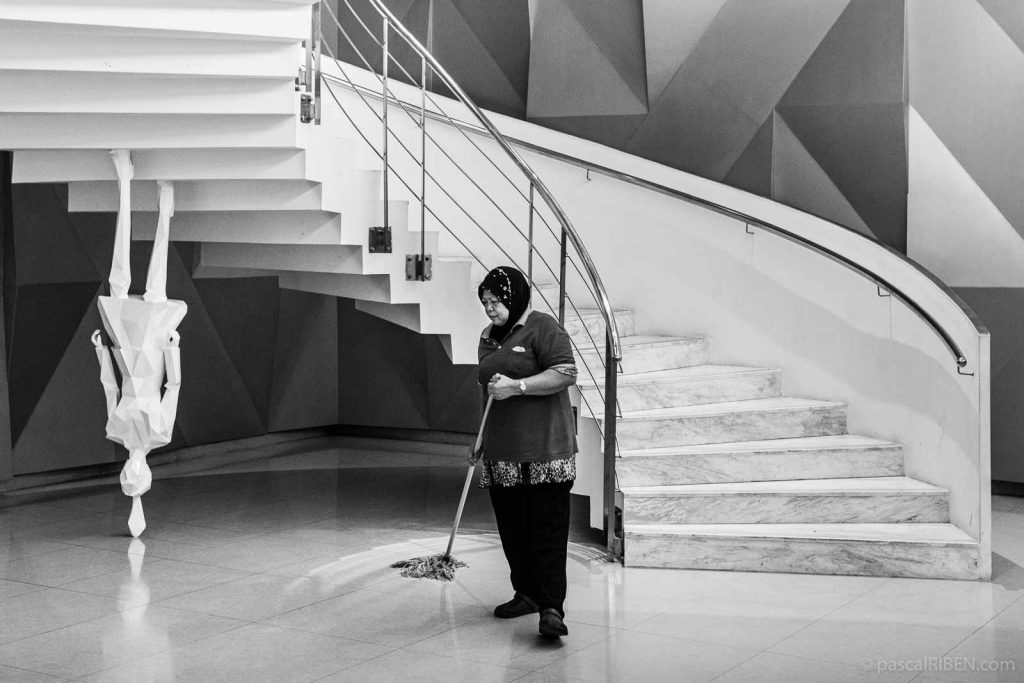 A cleaning woman is working near a statute in Kuala Lumpur, Malaysia.