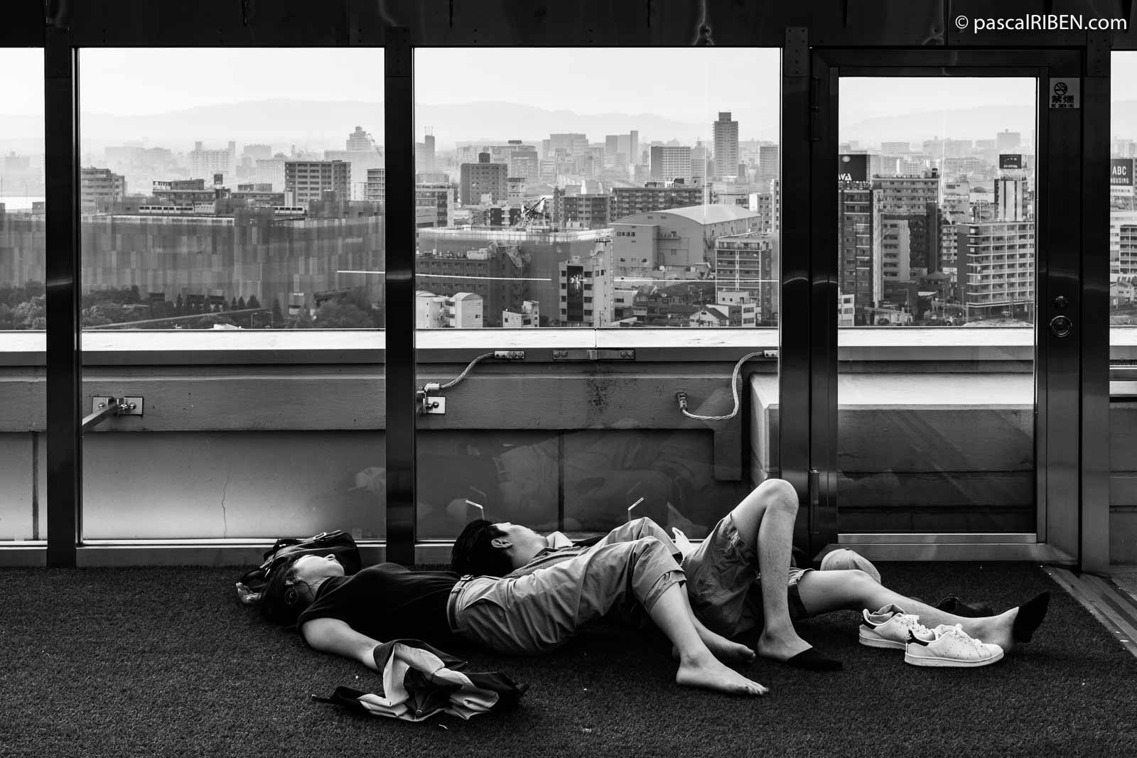A couple is taking a nap at Kaze-no-hiroba plaza, located on the 11th floor of Osaka Station City.