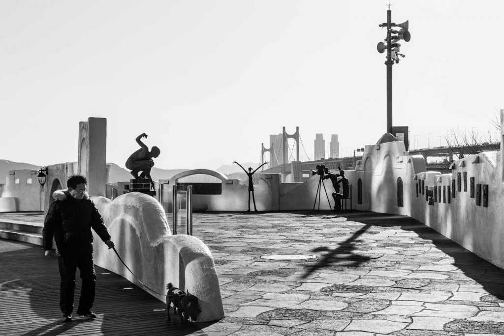 A man and his dog in front of Santorini Square, Busan, South Korea.